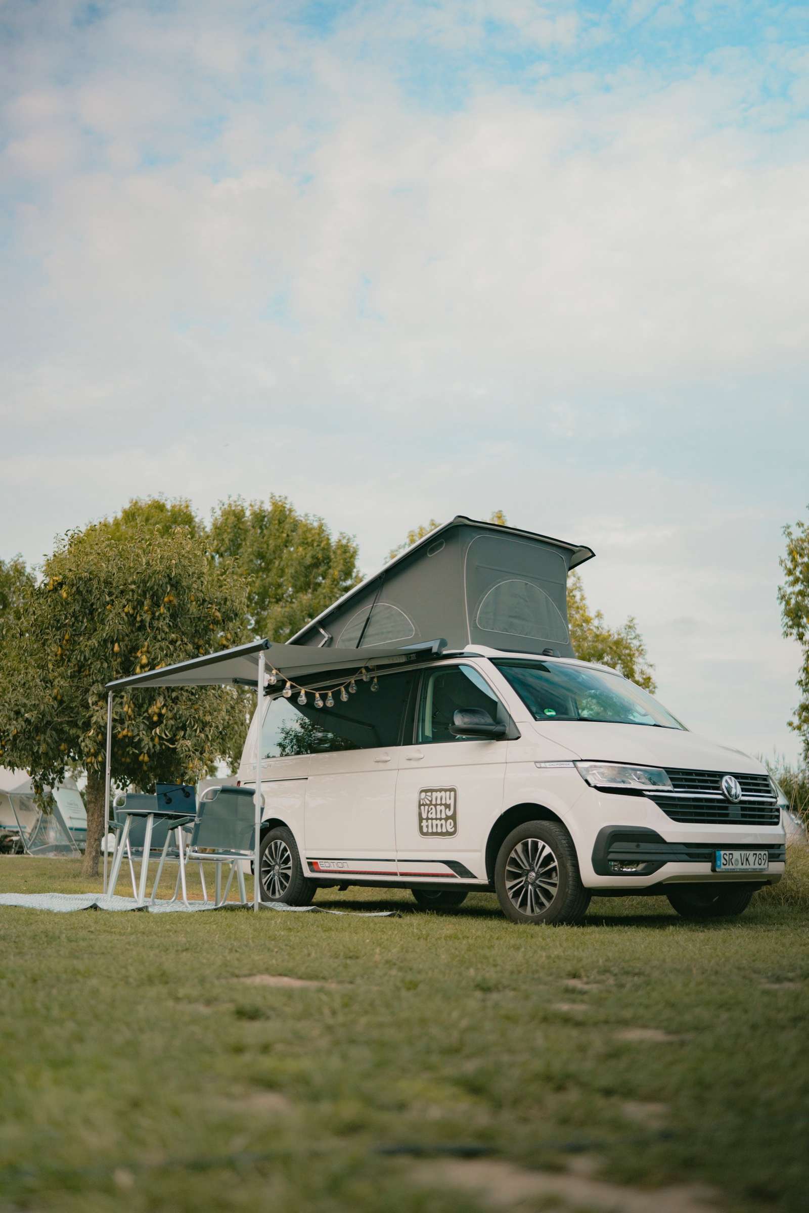 VW T6.1 California Beach mit aufgestelltem Dach auf dem Campingplatz — Camper mit Hund mieten bei My Vantime
